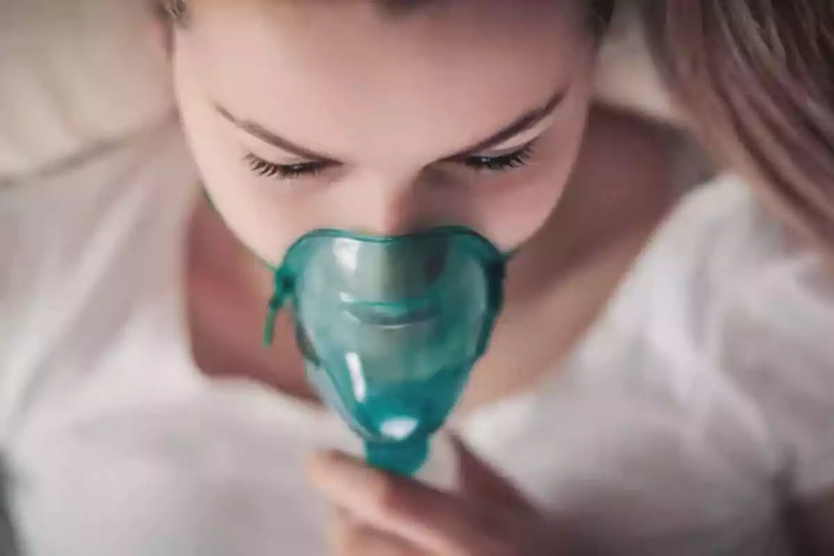 Fotografía de una chica estirada en una cama de hospital con un respirador en la boca