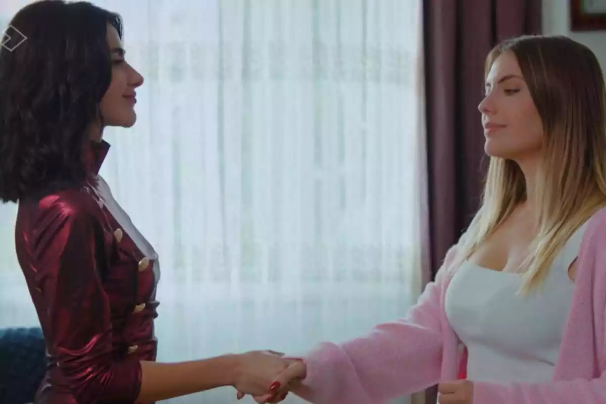 Captura de 'Pecado Original' con Sahika con un vestido rojo y Yildiz con una camiseta blanca y chaqueta rosa dándose la mano