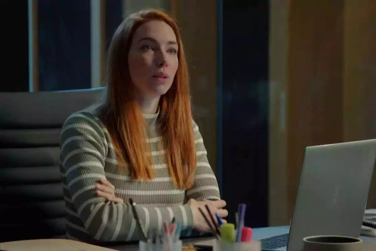 Captura de una secuencia de 'Mía es la venganza' con Olivia sentada en un escritorio
